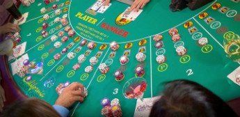 På bilden ser vi ett spelbord där personer spelar Baccarat