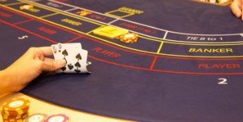 Enhand viker upp spelkort under en runda Baccarat